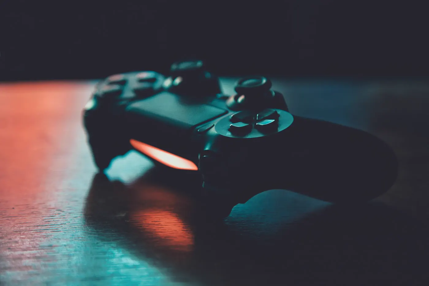 Game controller resting on a desk under warm and teal light